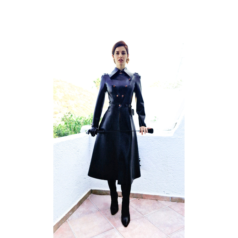 Model wearing a black riding coat with a big collar outdoors on a sunny day.