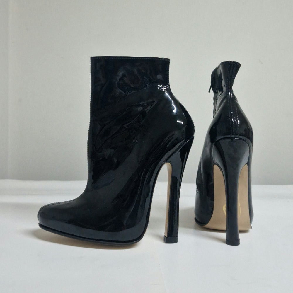 A pair of black patent leather ankle boots with high stiletto heels, shown from the side and back on a white surface against a light gray background.