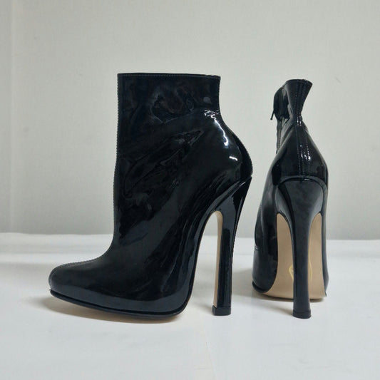 A pair of black patent leather ankle boots with high stiletto heels, shown from the side and back on a white surface against a light gray background.