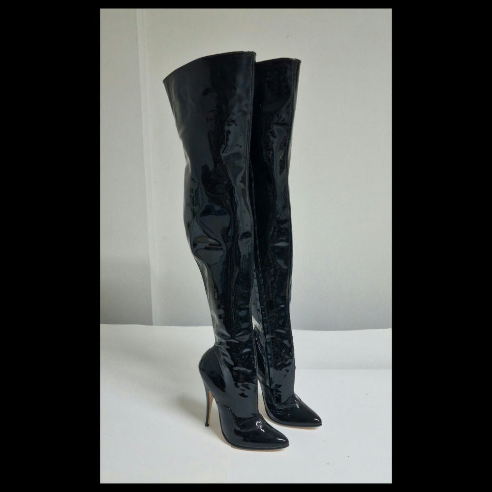 A pair of black patent leather over-the-knee boots with pointed toes and high stiletto heels, standing on a white surface against a white background.